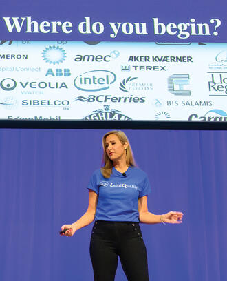 Lea Gabrielle Potts of LeadQualify at the MIT Delta V event presents on stage with the words "Where do you begin?" on screen