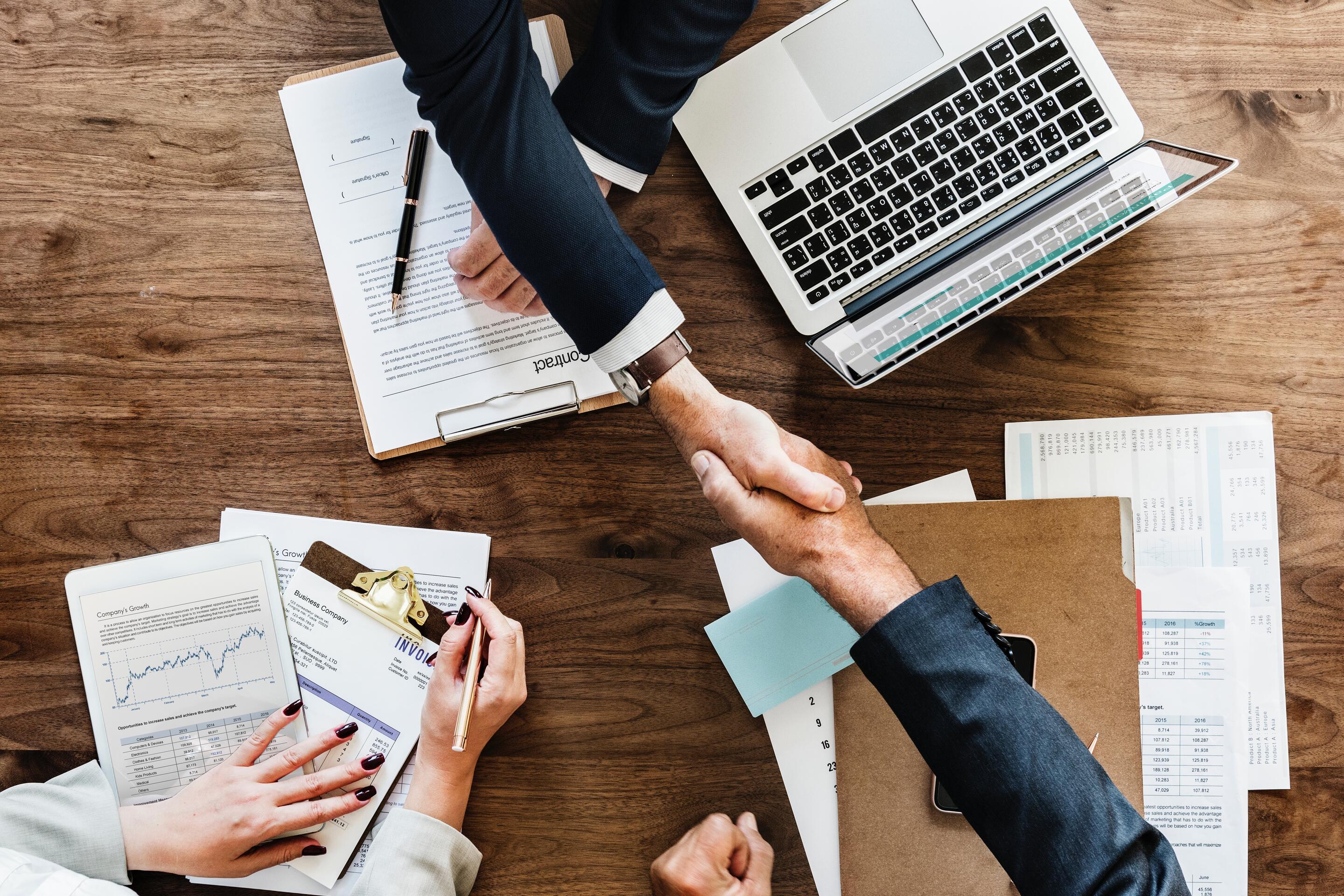 Men shaking hands over desk